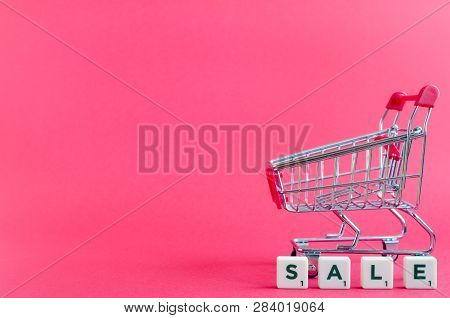Empty Grocery Cart And Word Sale On Pink Background. Trolley From A Supermarket. Online Shopping Con