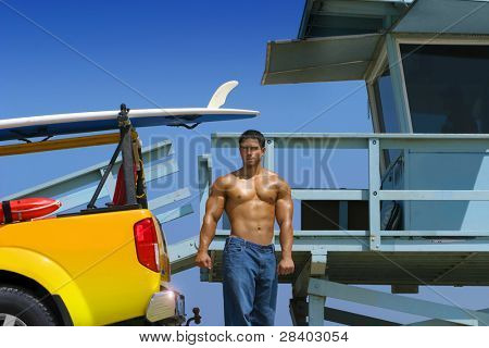 Hot hunky livredder på stranden med lastbil og livredder stander