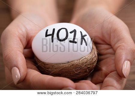 Close-up Of Human Hands Holding 401k White Egg In Nest
