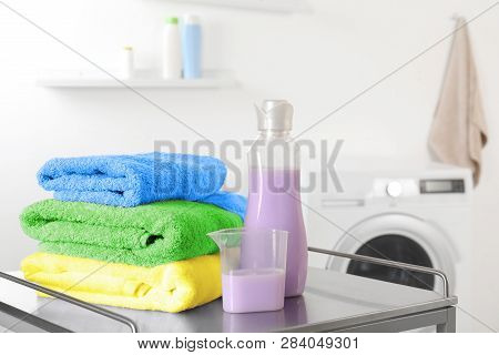 Clean Towels And Softener On Table In Laundry Room