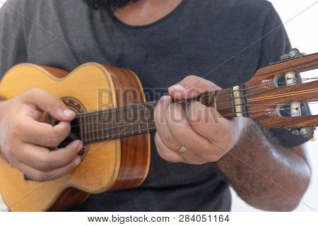 Young Man Playing Ukulele With Shirt And Black Pants.