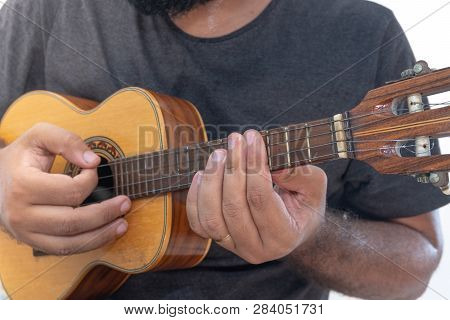 Young Man Playing Ukulele With Shirt And Black Pants.