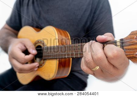 Young Man Playing Ukulele With Shirt And Black Pants.