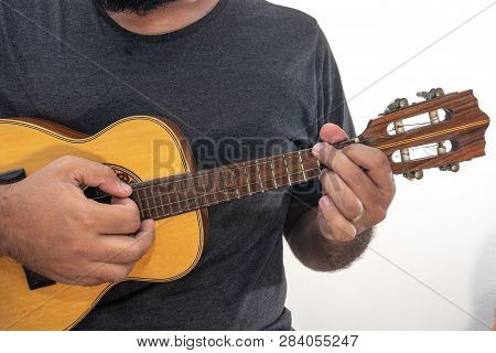 Young Man Playing Ukulele With Shirt And Black Pants.