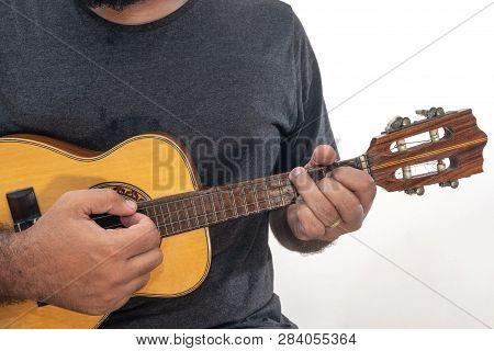 Young Man Playing Ukulele With Shirt And Black Pants.