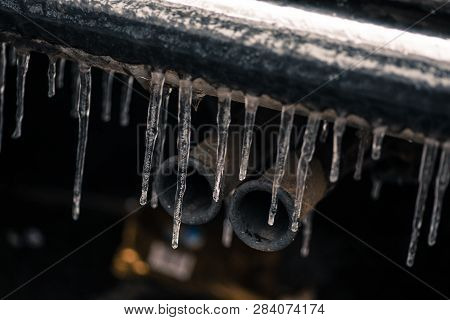 Close Up Shot Of Some Icicles On The Exhaust Pipe Of A Car.