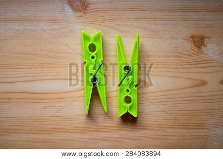 Two Bright Green Clothespins On The Wooden Table