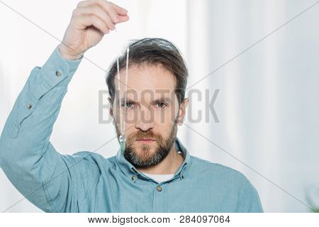 Serious Bearded Male Hypnotist Holding Dowsing And Looking At Camera