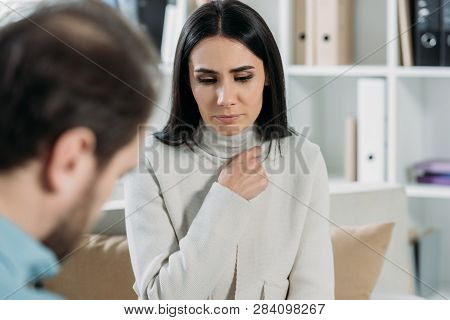 Selective Focus Of Unhappy Young Patient Looking Down While Talking With Psychotherapist In Office