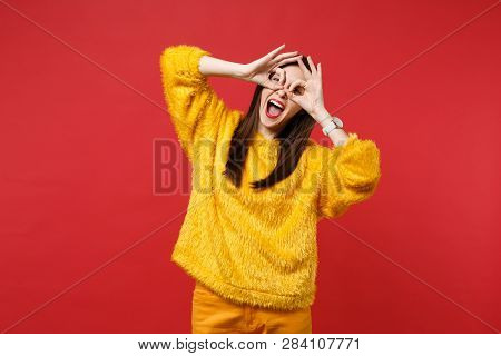 Funny Young Woman In Yellow Fur Sweater Holding Hands Near Eyes, Imitating Glasses Or Binoculars Iso