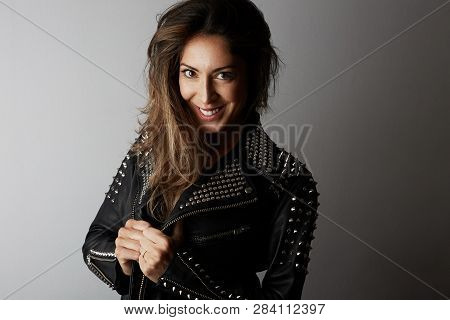 Fashion Photo Of A Beautiful Smiling Brunette Woman Wearing Leather Jacket With Dark Long Hair Posin