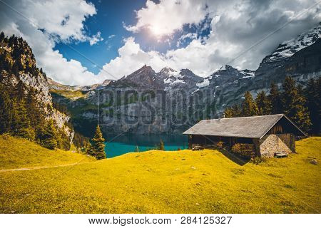 Idyllic panorama view of the lake Oeschinensee in day. Location place Swiss alps, Kandersteg, Bernese Oberland, Europe. Scenic image of most popular tourist attraction. Discover the beauty of earth.
