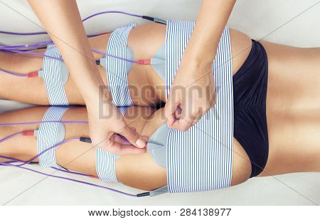 The Procedure Of Myostimulation On The Legs And Buttocks Of A Woman In A Beauty Salon. Caring For Th