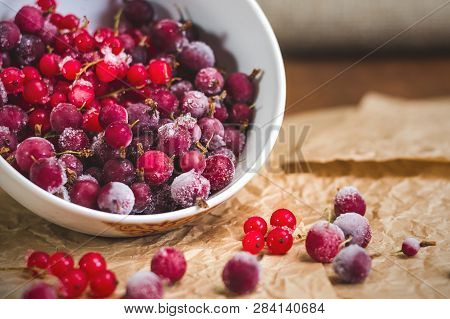 Red Frozen Berries Of Currant And Gooseberry, Covered With White Frost, In A White Plate And On The 