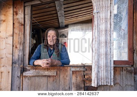 Muntele Bocului, Romania - February 7, 2019: Old rural woman called Lele Maria standing in the porch