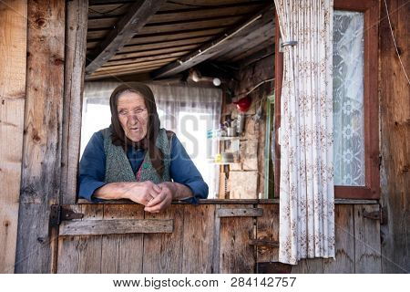 Muntele Bocului, Romania - February 7, 2019: Old rural woman called Lele Maria standing in the porch