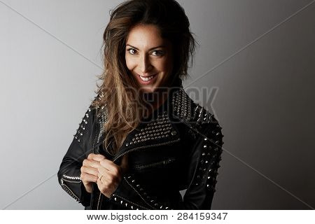 Fashion Photo Of A Beautiful Smiling Brunette Woman Wearing Leather Jacket With Dark Long Hair Posin