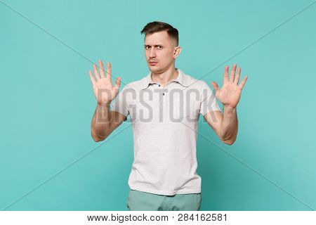 Portrait Of Perplexed Young Man In Casual Clothes Standing And Showing Palms Isolated On Blue Turquo