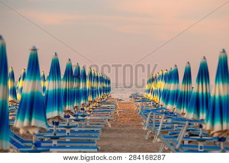Rimini, Italy. Rimini Beach With Blue Sun Umbrellas In The Evening. Rimini Seaside. Famous Resort In