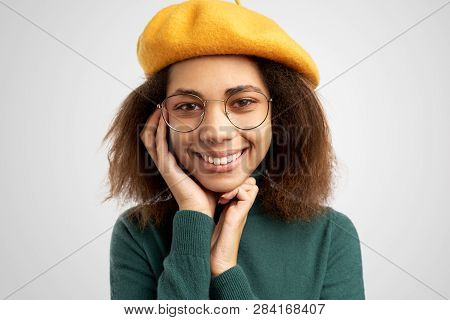 Young Female Nerd Wears Spectacles, Beret And Casual Green Sweater, Glad To Recieve Pleasant Comment