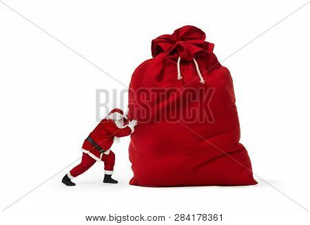 Close Up Of Santa Claus Pushing Huge Bag Of Presents Isiolated On White Background