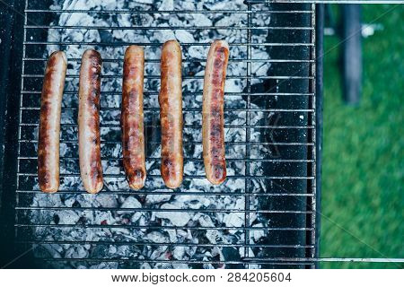 Top View Of Tasty Grilled Sausages On Bbq Grill Grade On Green Grass Background