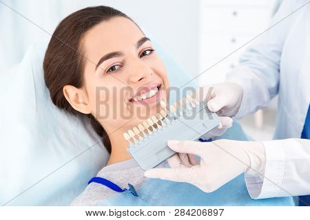 Dentist Selecting Patient's Teeth Color With Palette In Clinic