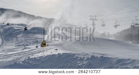 Snow Guns And Ski Lifts On Snow Covered Mountain