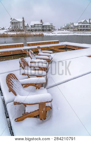 Snowy Chairs On Lake Deck With View Of Homes