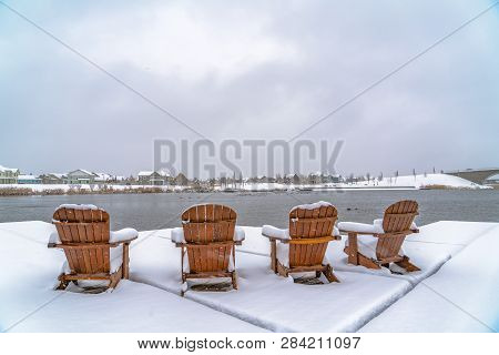 Wooden Chairs On Deck Overlooking Lake And Homes