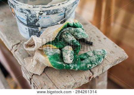Working Gloves. Do Makeovers. Putty Knife Lying On The Bucket. Tools For Construction And Repair. Se