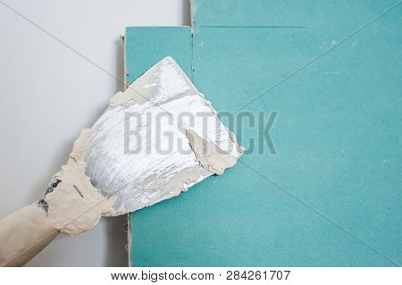 Spatula With Putty. The Process Of Applying The Paste On The Blue Gypsum. Repair Work, Decoration Bu