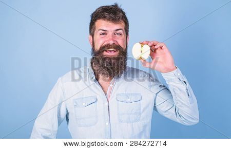 Man Bearded Smiling Holds Apple Blue Background. Healthcare Dieting Vitamin Nutrition. Half Of Apple