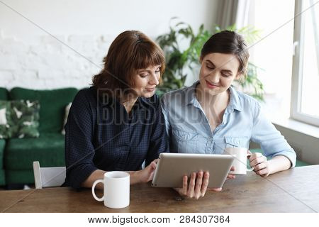 lifestyle, tehnology and people concept: mother and adult daughter using tablet computer at home, close up