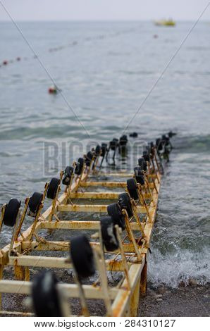 Rails With Wheels Go Under The Water Of A Large Lake. Rails For Launching Boats