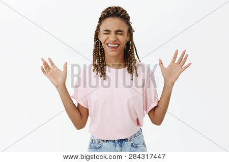 Amused And Joyful Carefree African-american Woman With Dreads In Pink T-shirt Closing Eyes Raising A