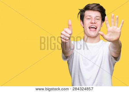 Young handsome man wearing casual white t-shirt over isolated background showing and pointing up with fingers number six while smiling confident and happy.