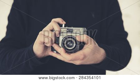 A Midsection Of A Male Photographer Focussing A Lens Whilst Holding A Retro Or Old Fashioned 35mm Ca