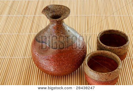 Bouteille de Sake et deux tasses sur une natte de bambou