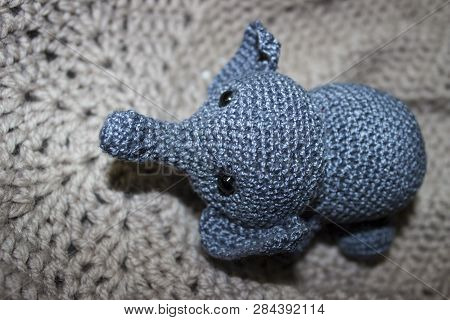 Little Grey Elephant Crocheted Sitting On Knitted Texture With Patterns