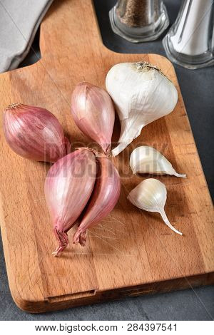 Overhead View Of Fresh Shallots And Garlic On A Cutting Board