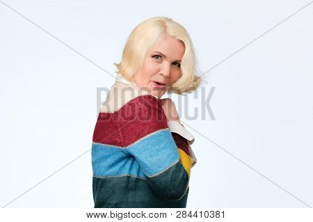 Senior European Woman Hides Something In Her Hands And Looks Warily Forward