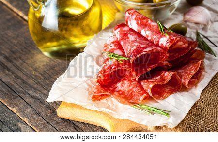 Italian Salami With Olives And Spices On Wooden Background