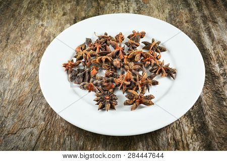 Chinese Star Anise Spice Fruit On White Plate On Wood Background - Other Names Star Aniseed , Badian