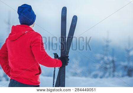 Winter Season Sports Theme. Caucasian Skier With Skis In Hand Closeup Photo.