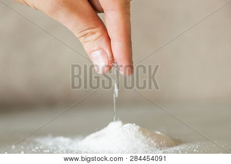 A Close-up Of A Hand Pours A Hill Of Salt. Microplastic Problem In Salt.