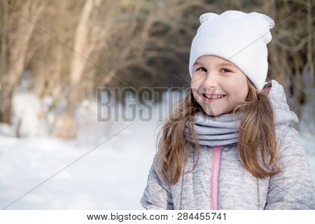 Portrait Of A Beautiful Little Girl In Winter Park, Smle And Lifystyle Dress