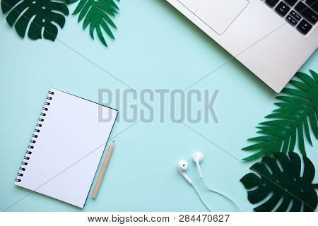 Workspace In A Trendy Blue Color. Many Different Items Including A Laptop, Notebook, And Headphones 