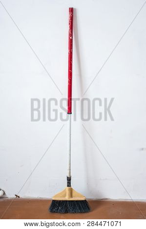 Close Up Of Red Black Broom On White Background. Cleanliness Concept