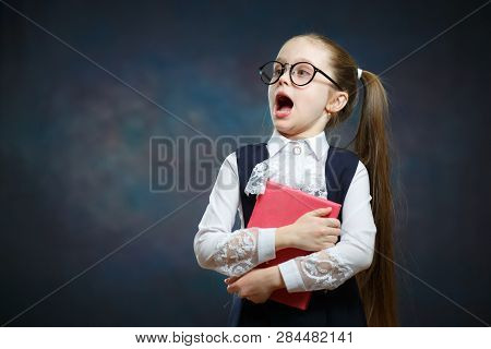 Caucasian Schoolgirl With Open Mouth Hold Book. Suprised Elementary School Girl In Glasses And Forma
